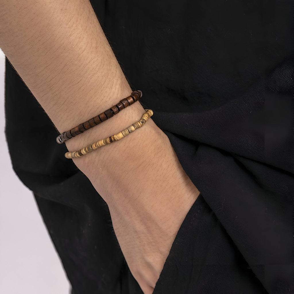 Deux bracelets en bois pour homme, l’un marron foncé et l’autre beige clair, style naturel et ajusté au poignet.
