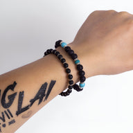 Deux bracelets homme en pierres volcaniques noires, l'un avec perles bleues et turquoise, style moderne.