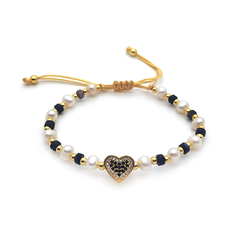 Bracelet ajustable noir et blanc en perles avec cœur doré orné de strass noirs.